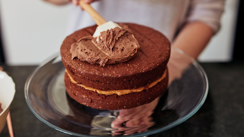 Person spreading frosting on cake