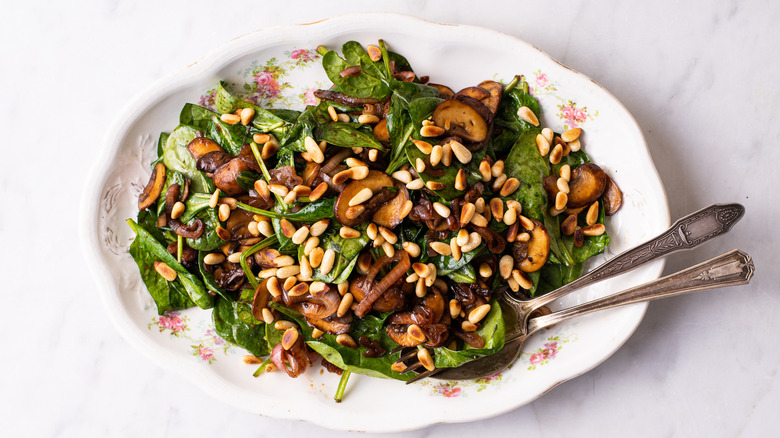 Warm wilted spinach salad on an oval platter.