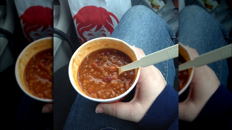 Someone holding Wendy's chili with spoon