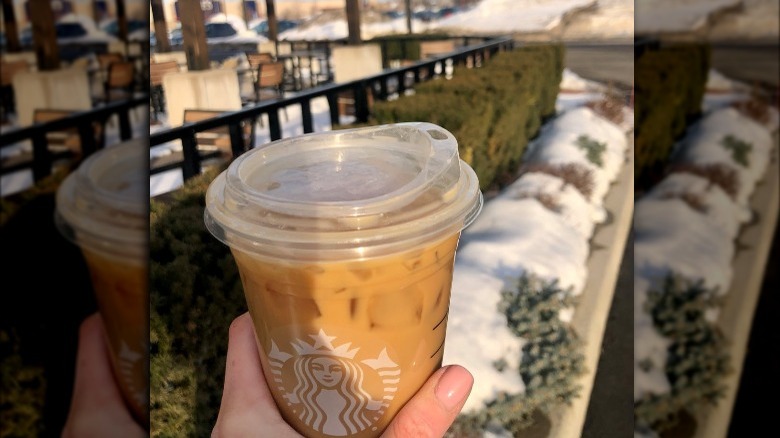 Someone holding Starbucks Iced Coffee outside