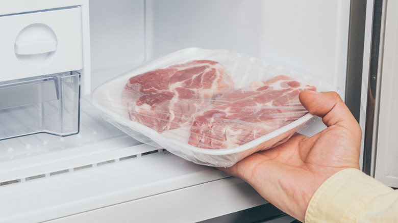 Hand removing meat from freezer