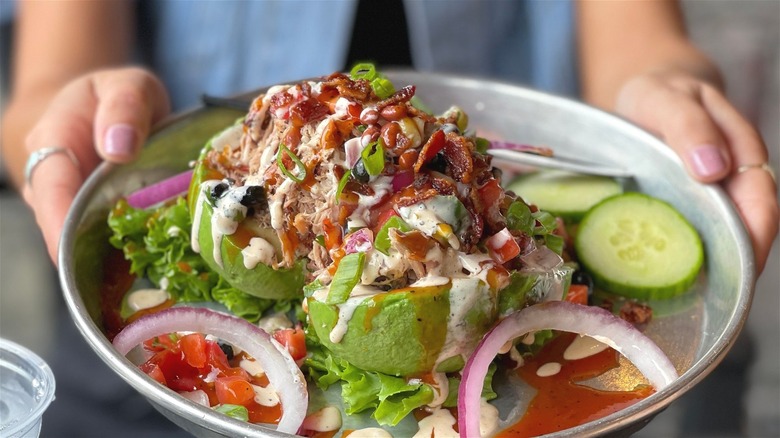 Woman holding plate stuffed avocados