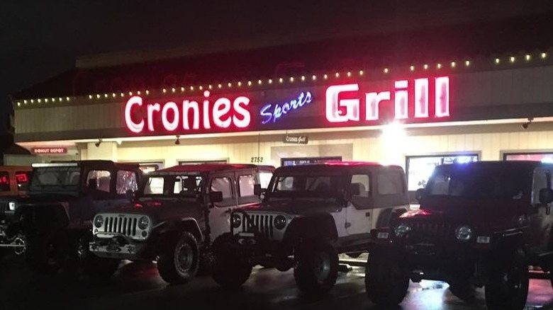 Neon sports grill sign over cars