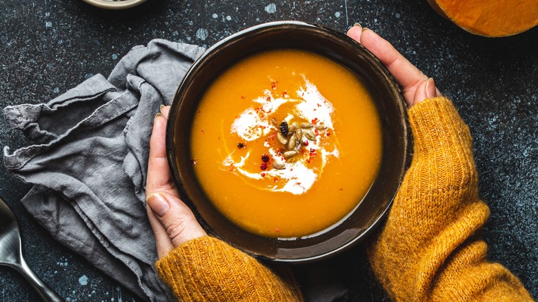 hands holding bowl of soup