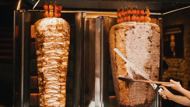 hand slicing meat off spit