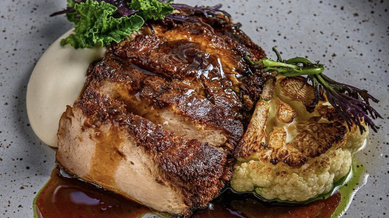 Closeup of roasted Lion's Mane mushroom and cauliflower with sauce and greens