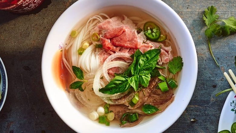 plated beef pho with sriracha on grey background