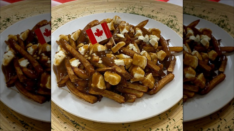 Poutine on white plate with small Canadian flag