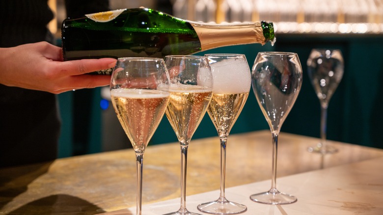 person pouring glasses of sparkling wine