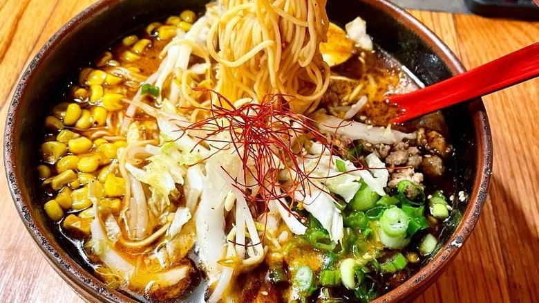 Ramen noodles pulled from bowl of corn and broth