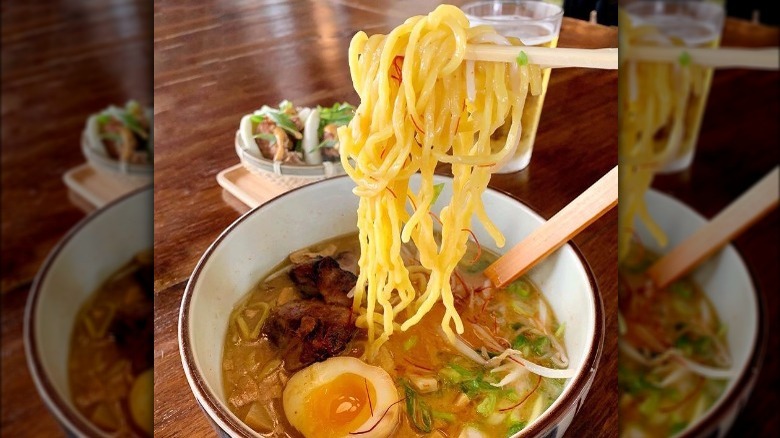 noodles held over soup bowl