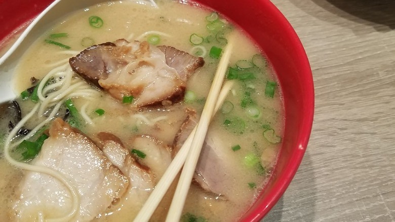 red bowl with creamy broth and chopsticks