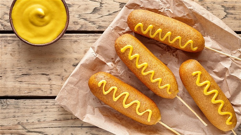 Four corn dogs with mustard