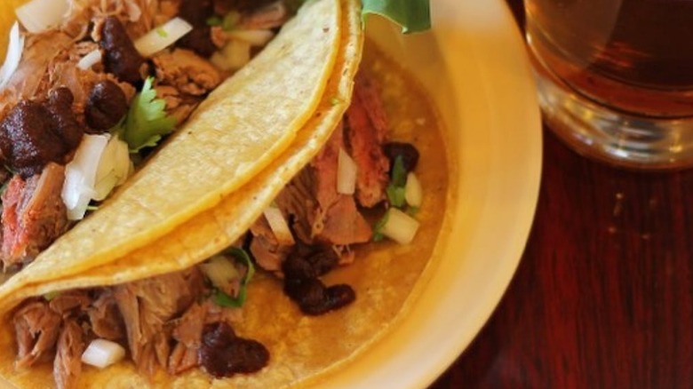 close up of lamb barbacoa tacos with onions and cilantros on plate