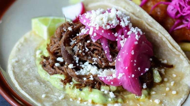 close up of barbacoa tacos with cotija and pickled red onions