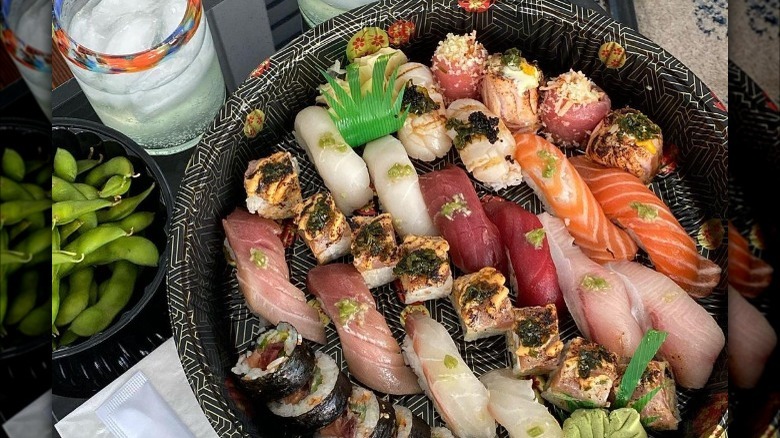 A round plate with various pieces of raw fish and sushi rolls