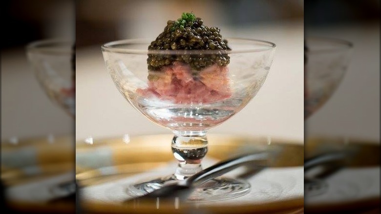 A glass chalice filled with raw fish and roe