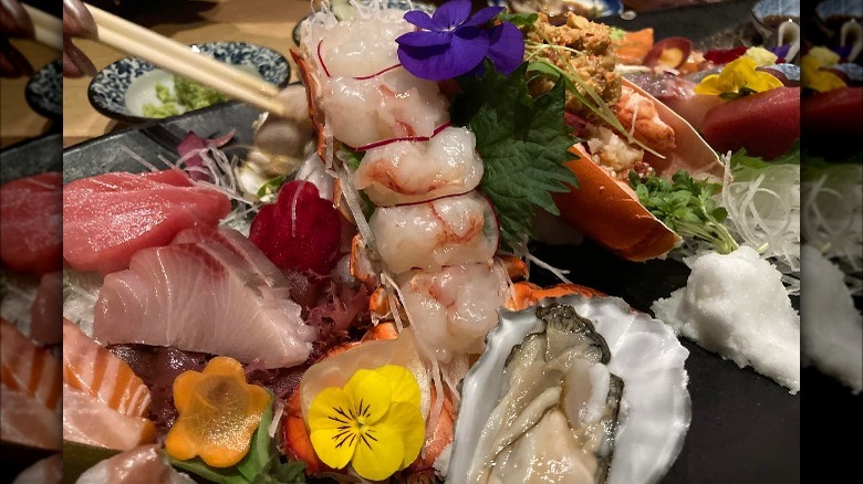 A collection of raw fish, scallops, and multicolored flowers