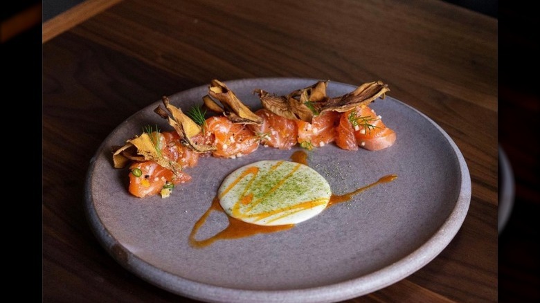 A round grey plate with fried plantains and orange fish