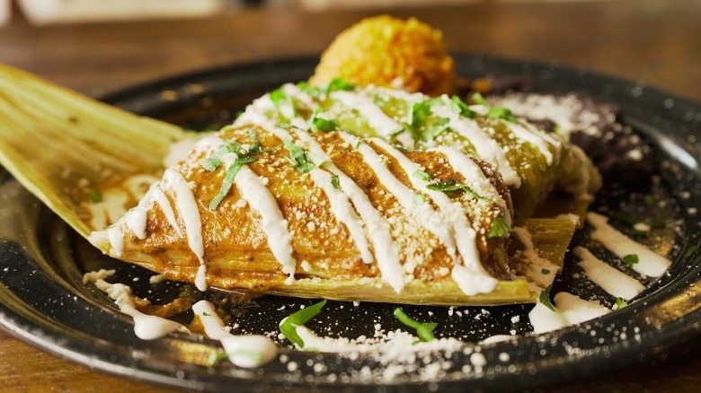 two tamales topped with mexican sour cream and cojita cheese