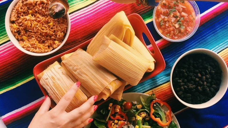 tamales with rice vegetables and beans on a mexican blanket