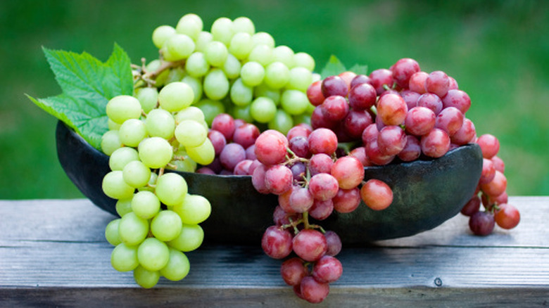 red and green grapes in a rustic bowl set on an outdoor table