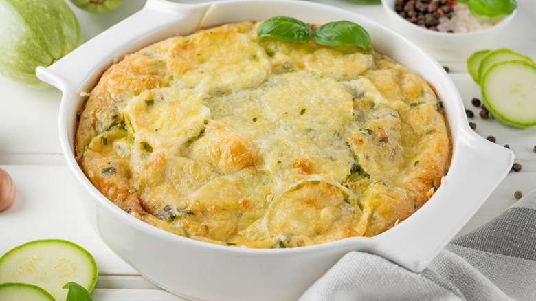 A zucchini casserole cools in a white dish.