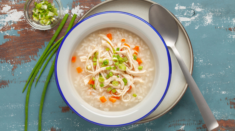 A bowl of soup includes rice with green onions and other vegetables.