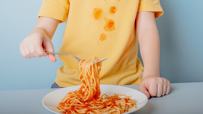 Kid eating spaghetti messily 