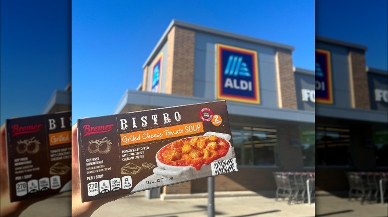 Person holding a box of Bremmer Bistro grilled cheese tomato soup in front of an Aldi store.