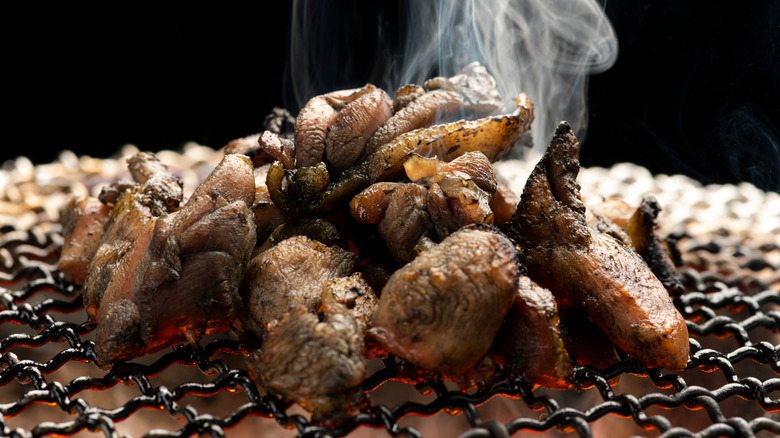 Chicken chunks sizzling on yakitori grill