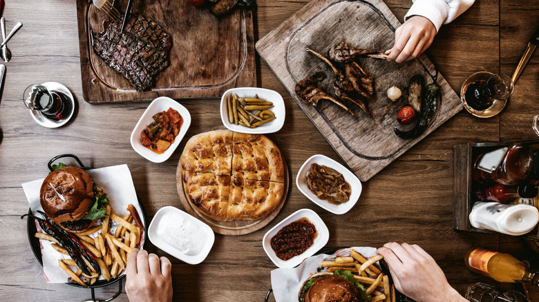 table with steak, burgers, side dishes, and bread