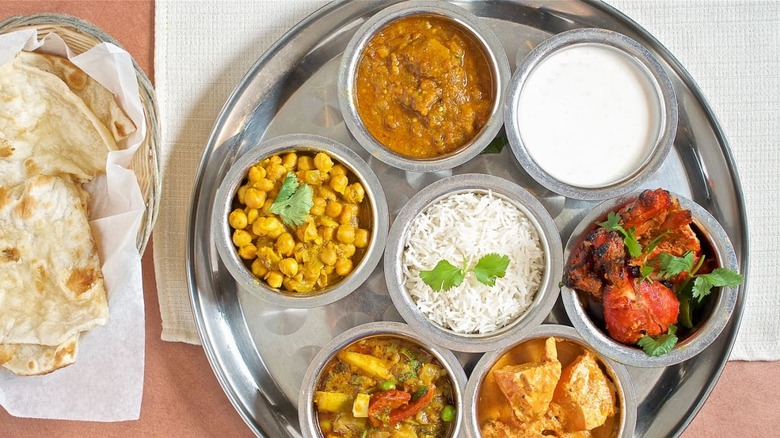 Chickpeas, rice, chicken, naan on a silver platter.