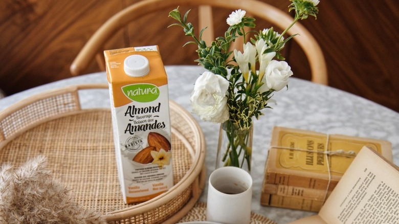 A tray with almond milk, books, and a vase of flowers