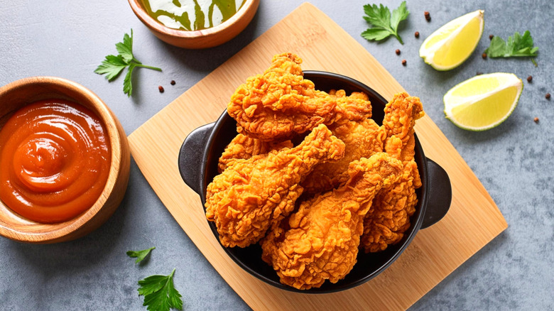 Fried chicken in a black bowl with condiments