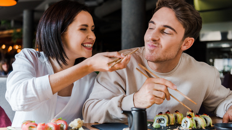 couple feeds sushi with chopsticks