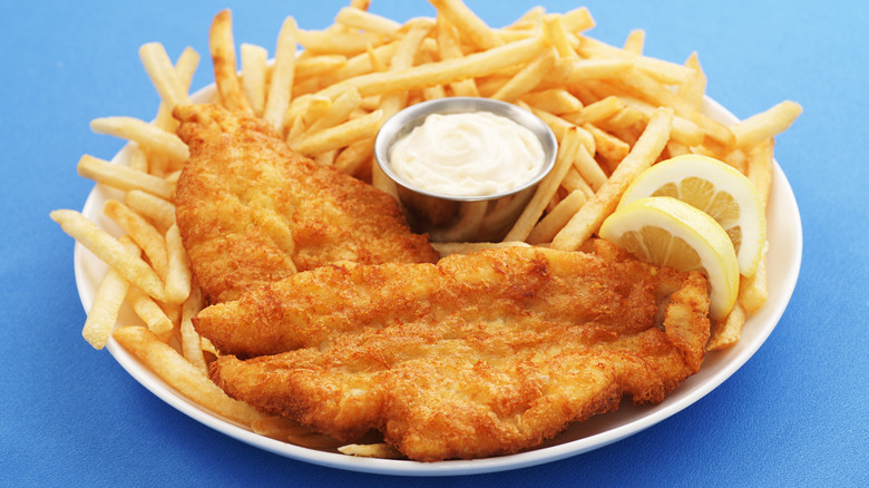 fish and chips on white plate with tartar dipping sauce