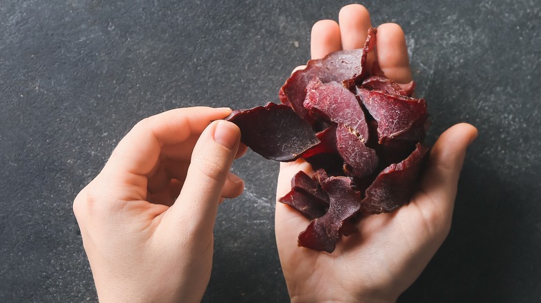 two hands holding beef jerky