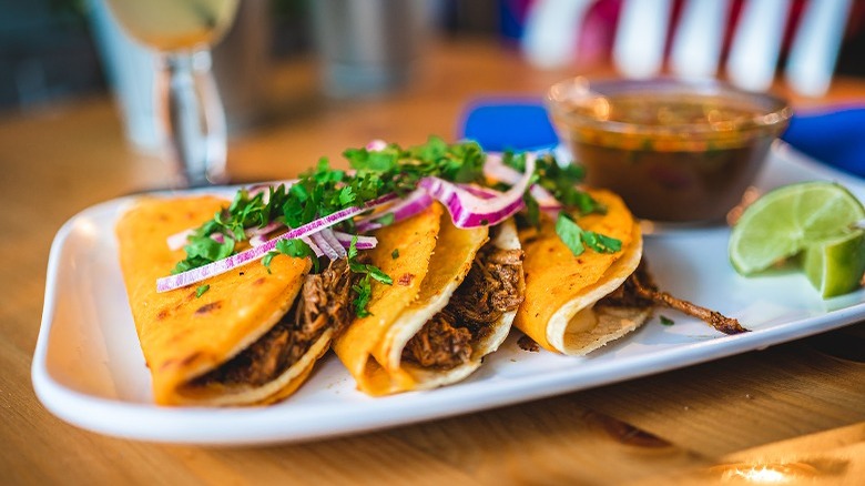 Three birria tacos on platter