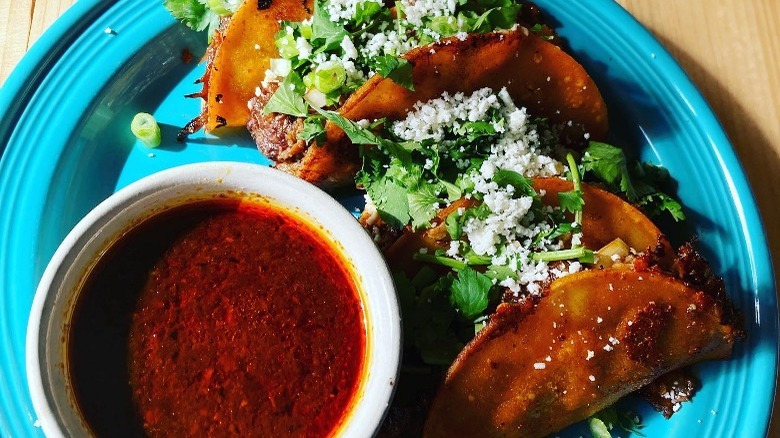 Four birria tacos with consomé