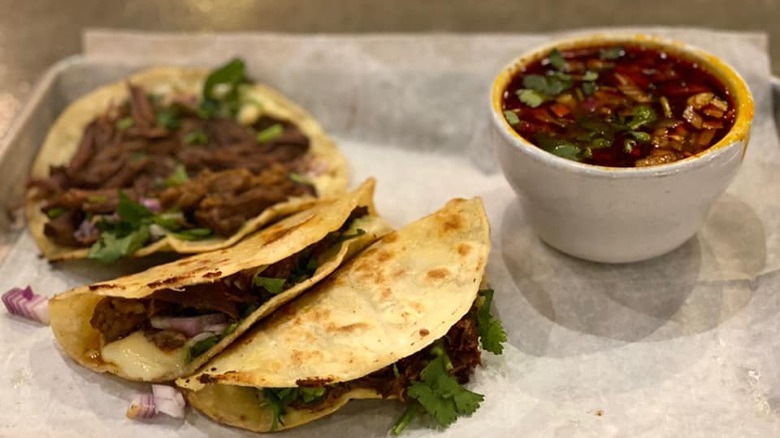 Three birria tacos with consomé