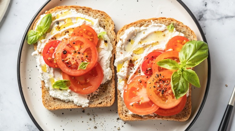 Tomato slices with other sandwich ingredients on two pieces of bread