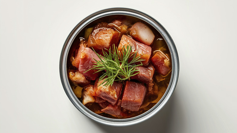 top view of open can of roast beef in broth with rosemary on top