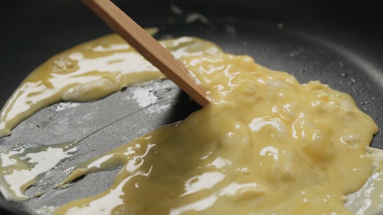 Spoon scraping pan to scramble eggs