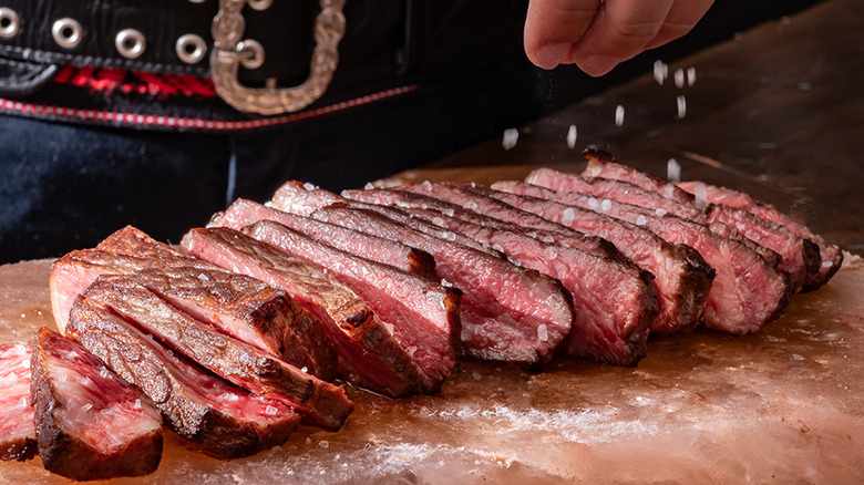 Hand salting sliced steak at Fogo de Chão