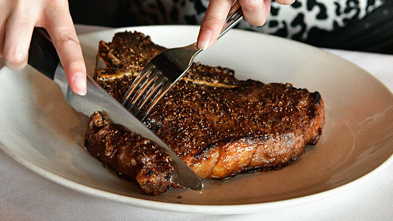 Knife and fork cutting Del Frisco's steak