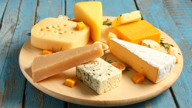 a plate full of various types of cheese on a rustic wooden table