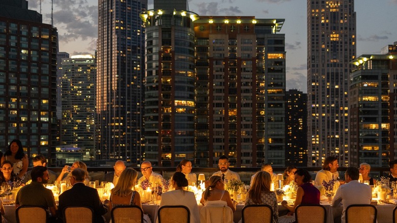 diners sitting at long table outside with views of Chicago