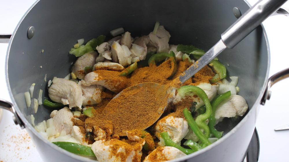 stirring chicken curry spices in pot