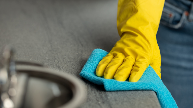 gloved hand cleaning countertop